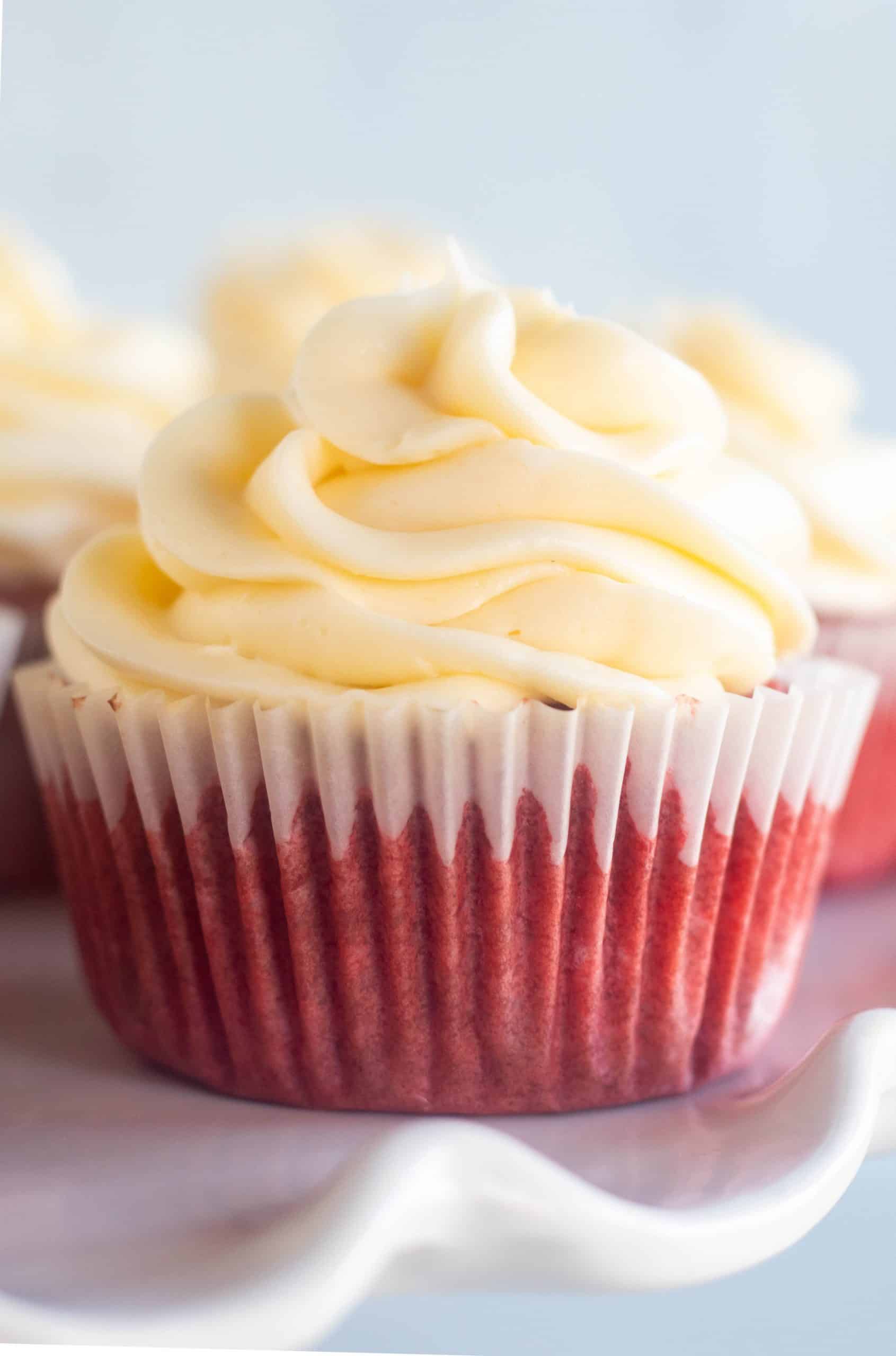 close up of red velvet cupcake with piped cream cheese frosting.