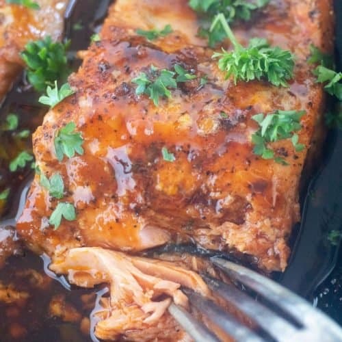 close up of a fork cutting a piece of salmon