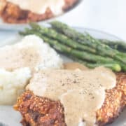 plated chicken fried steak with gravy, mashed cauliflower, and asparagus