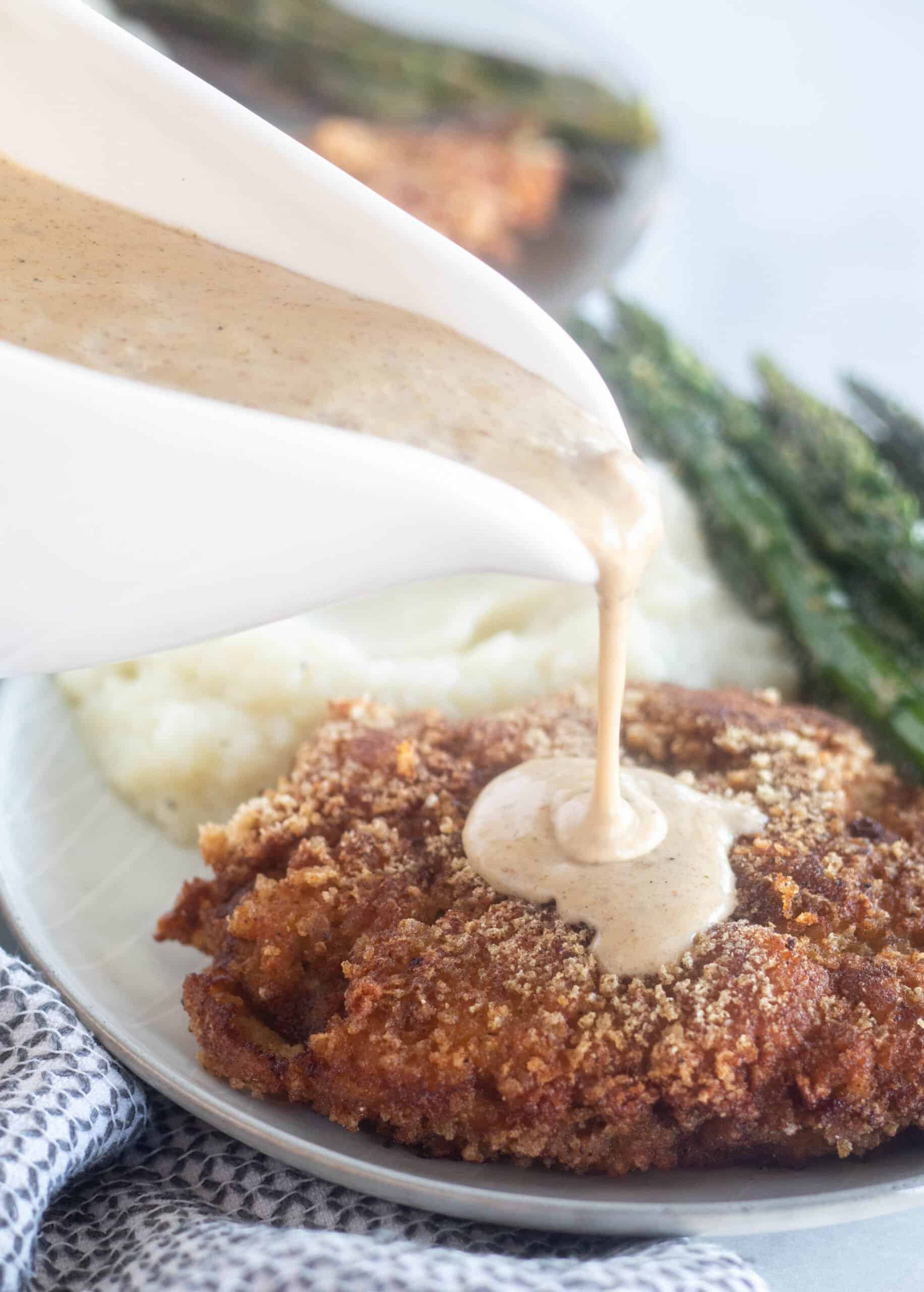 pouring gravy over the chicken fried steak.