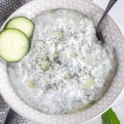 tzatziki sauce in a bowl with sliced cucumber