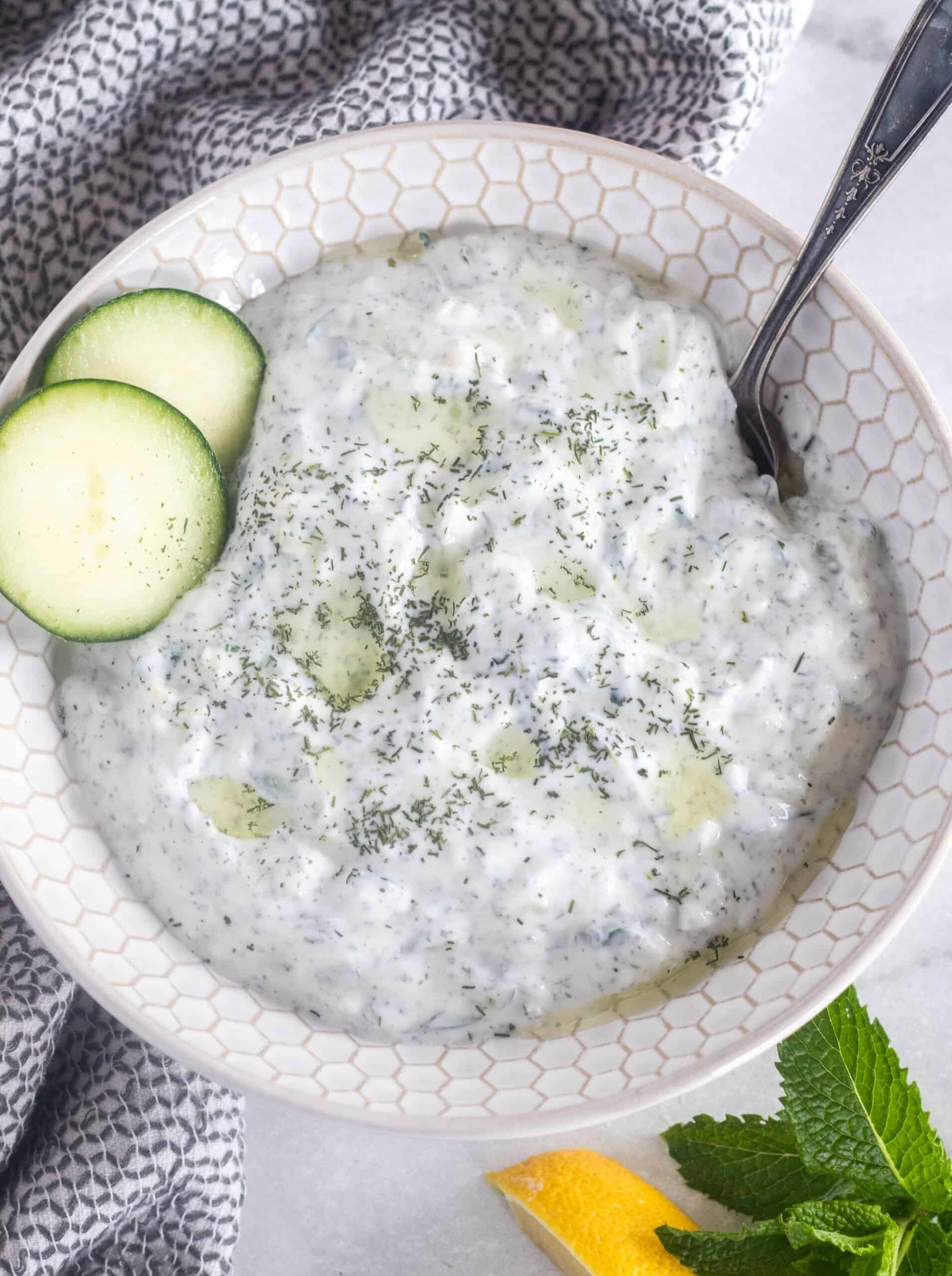 tzatziki sauce in a bowl with sliced cucumber