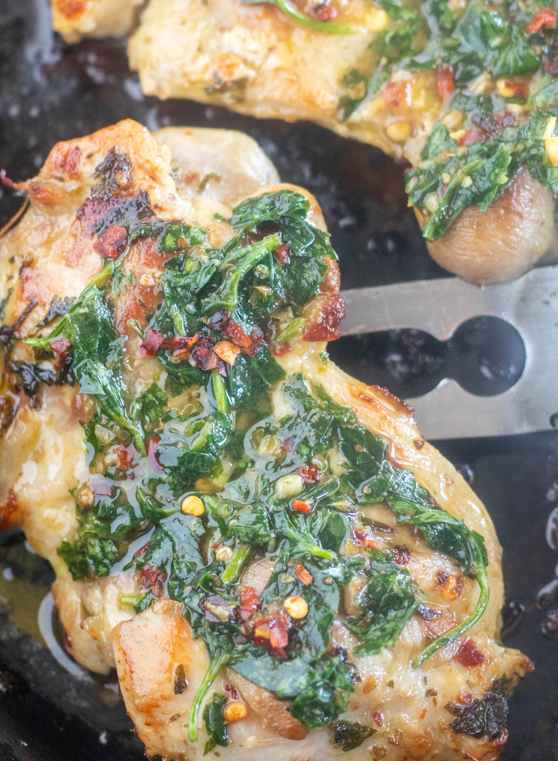 grilled chicken with chimichurri sauce spooned over top in a skillet