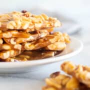 sugar-free peanut brittle stacked on a white plate.