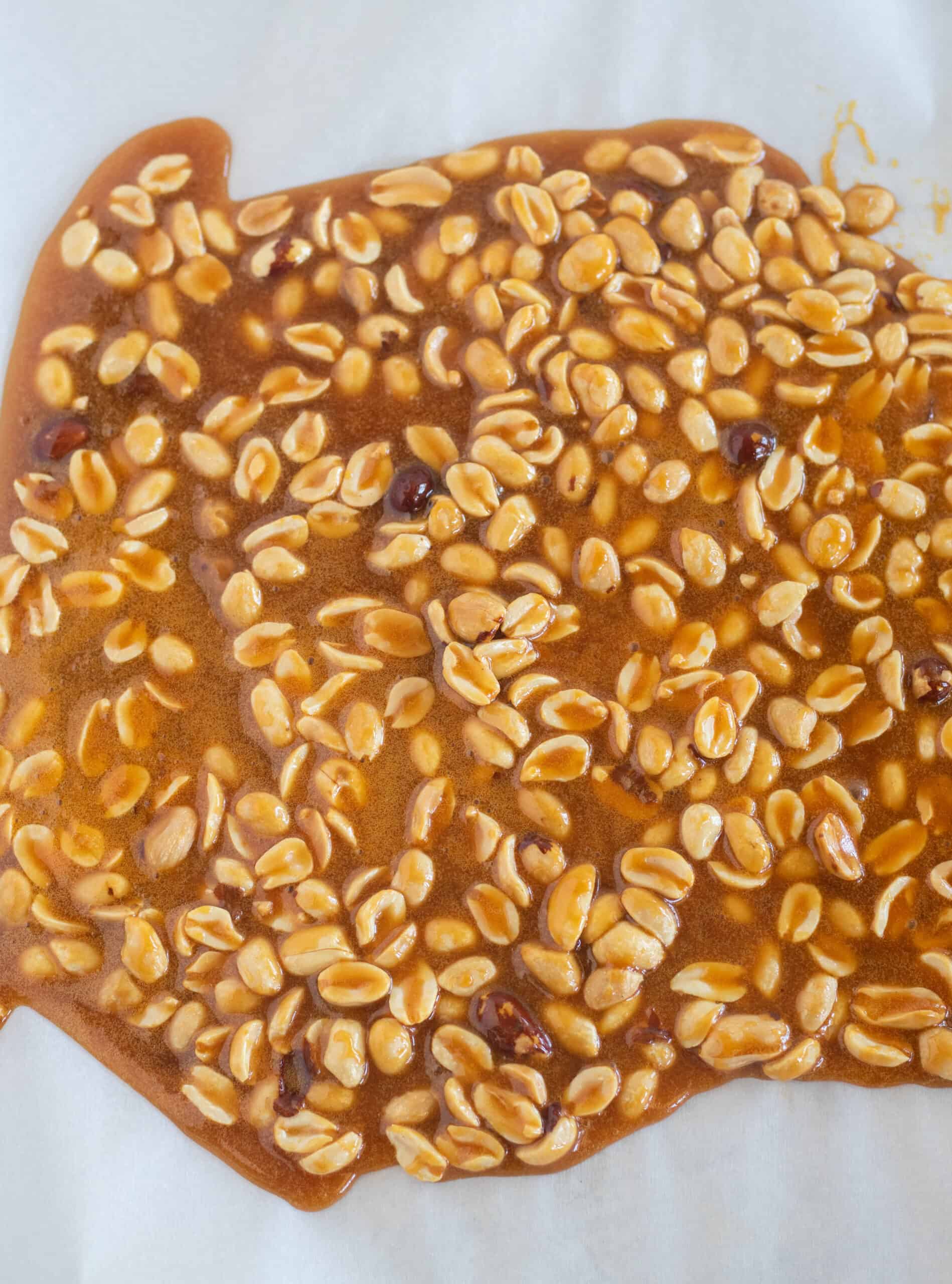 peanut brittle spread out on a lined baking sheet.