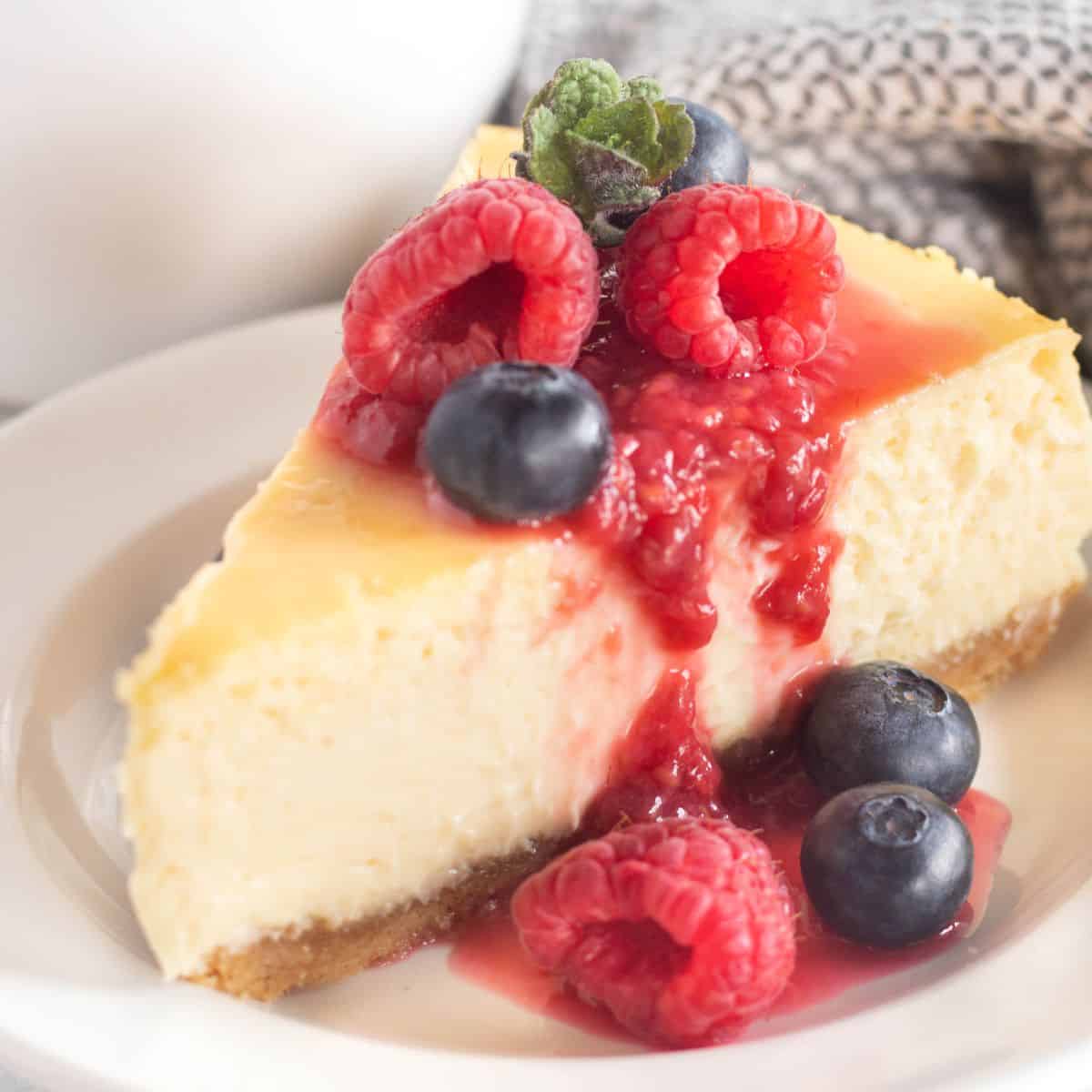 square image of a slice of cheesecake with berries.