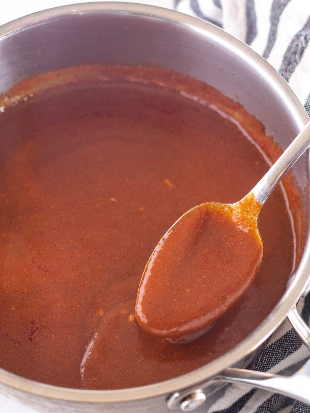 spooning sauce out of a pot.