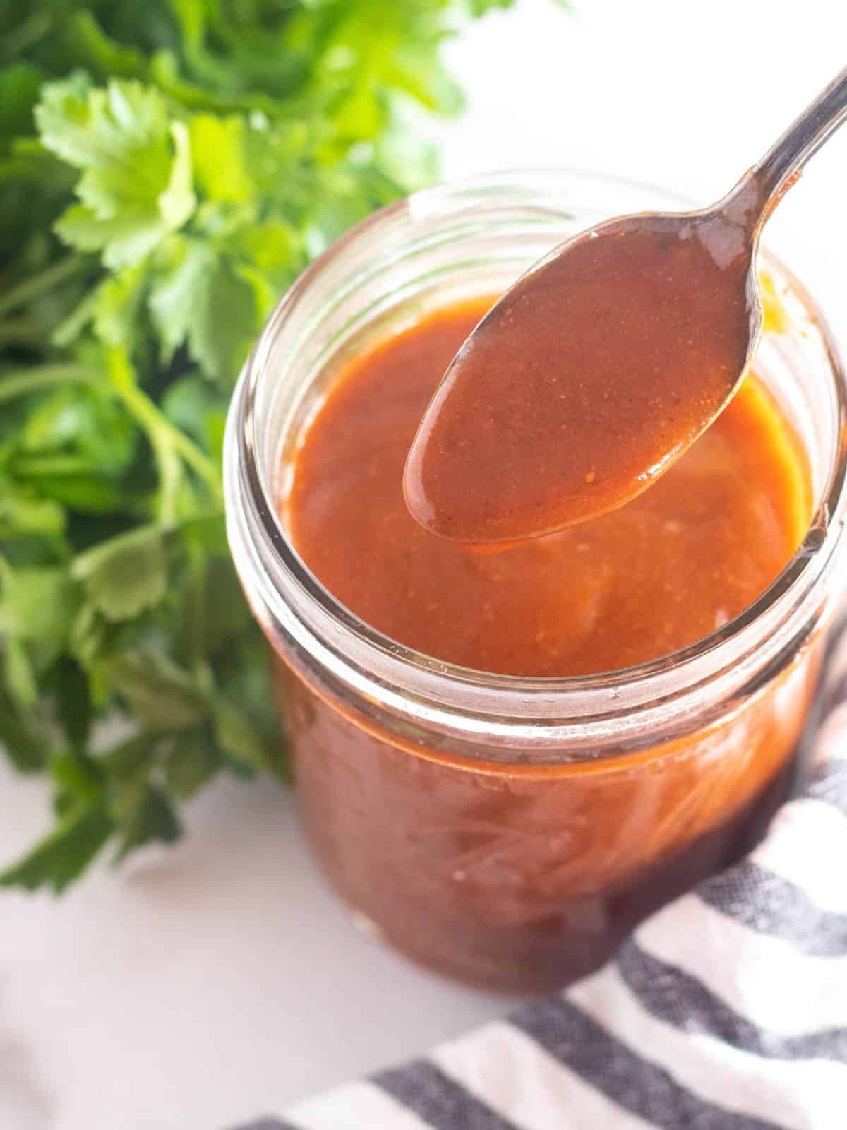 spooning enchilada sauce out of a mason jar.