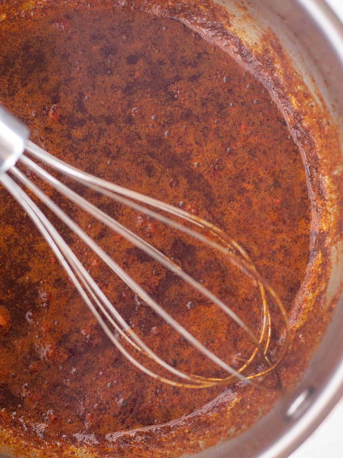 sauce in a pot with a whisk.