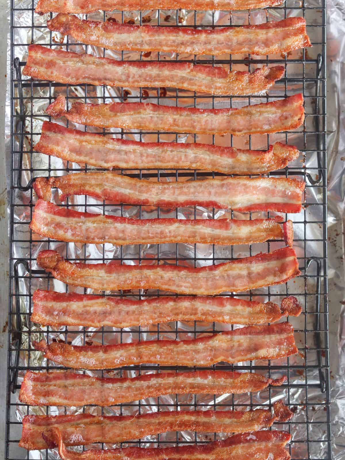 cooked bacon on a cooling rack inside a baking sheet.