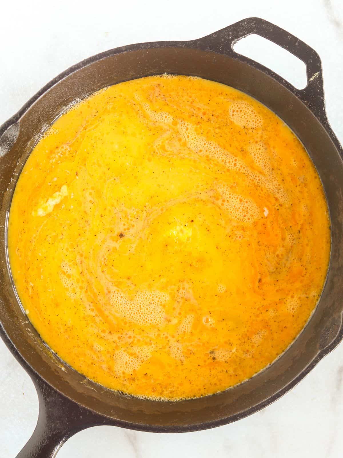 bottom of the eggs starting to set in a cast iron skillet.