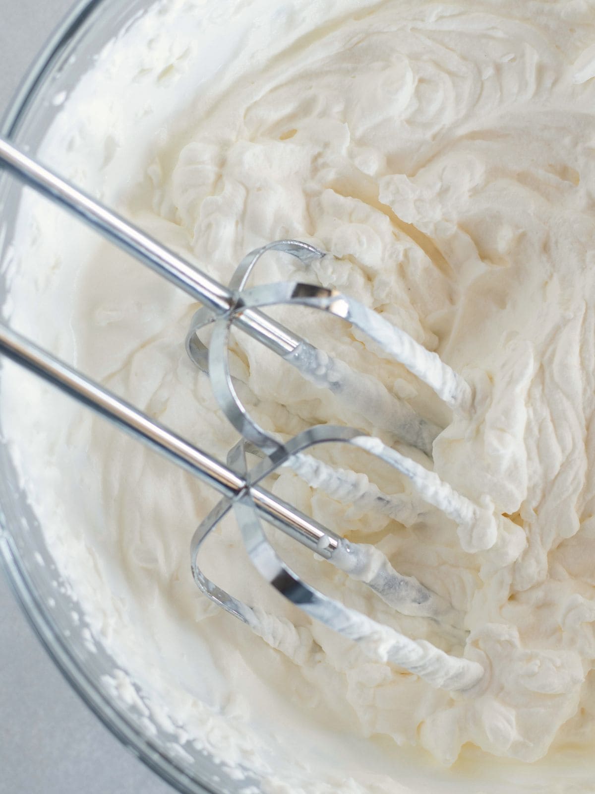 beaten whipped cream in a bowl with beaters.